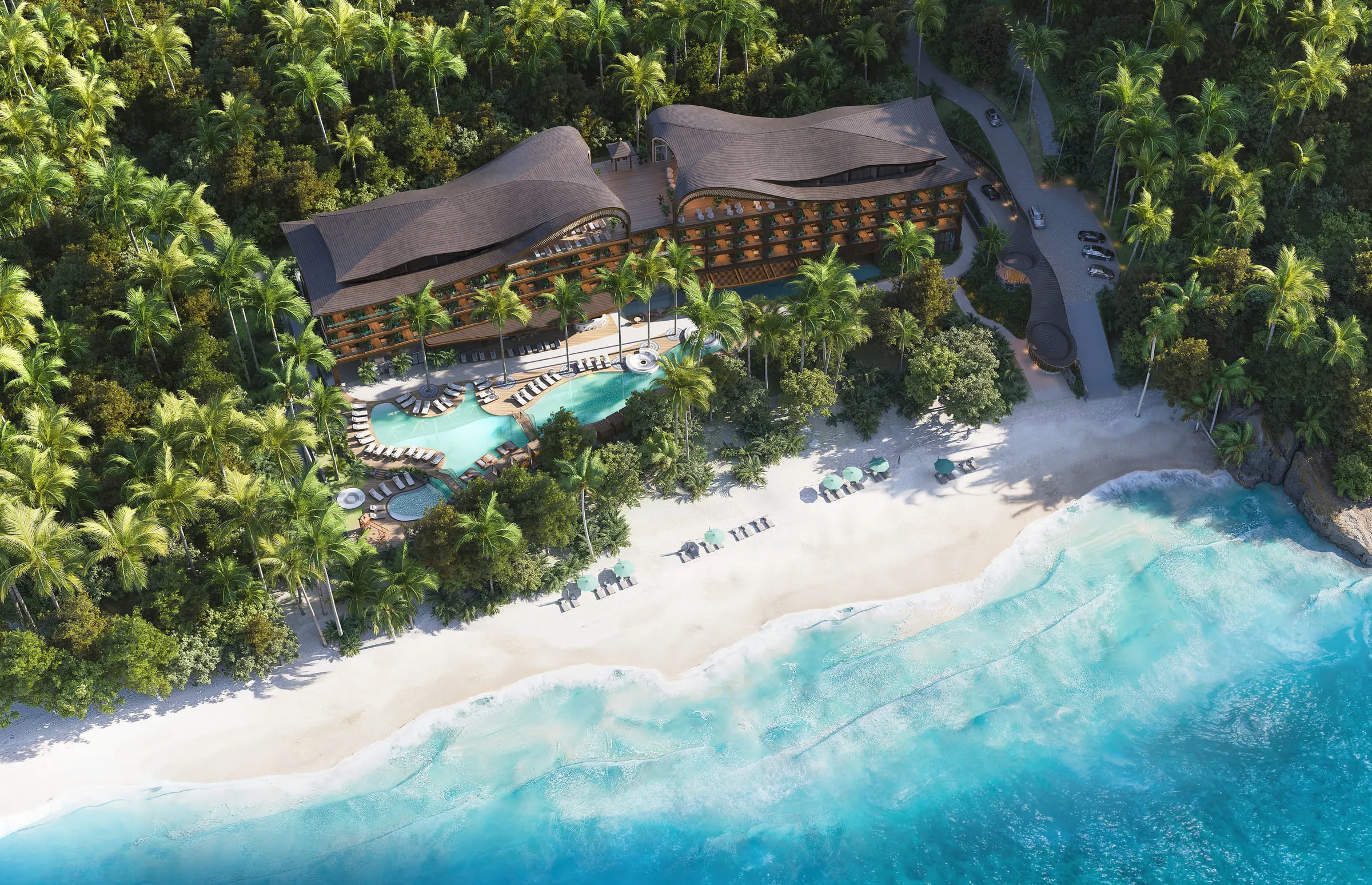 Aerial view of a thatched-roof beachfront resort with curved swimming pools, palm trees and a white sand beach.